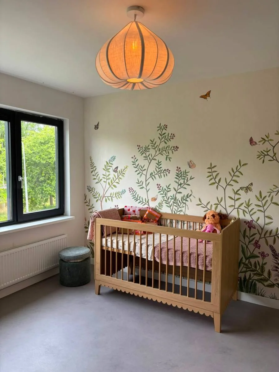 Babykamer met botanische muurschildering en eiken ledikant