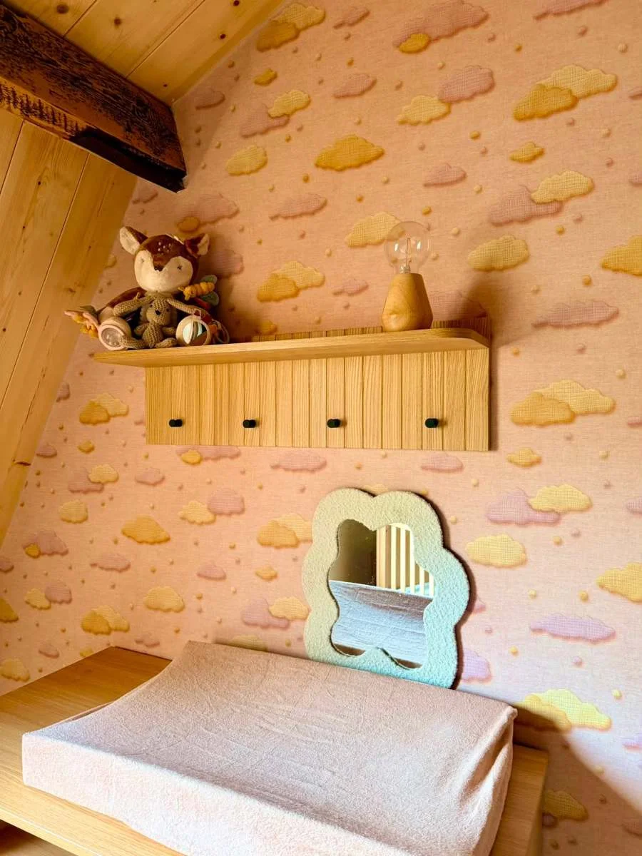 Babykamer met wolkjesbehang, houten wandplank en golvende spiegel