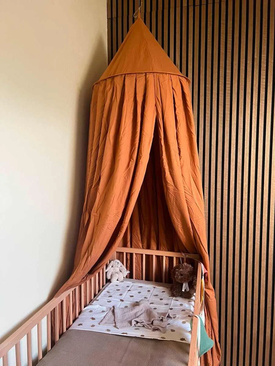Babykamer met terracotta klamboe boven een beuken ledikant